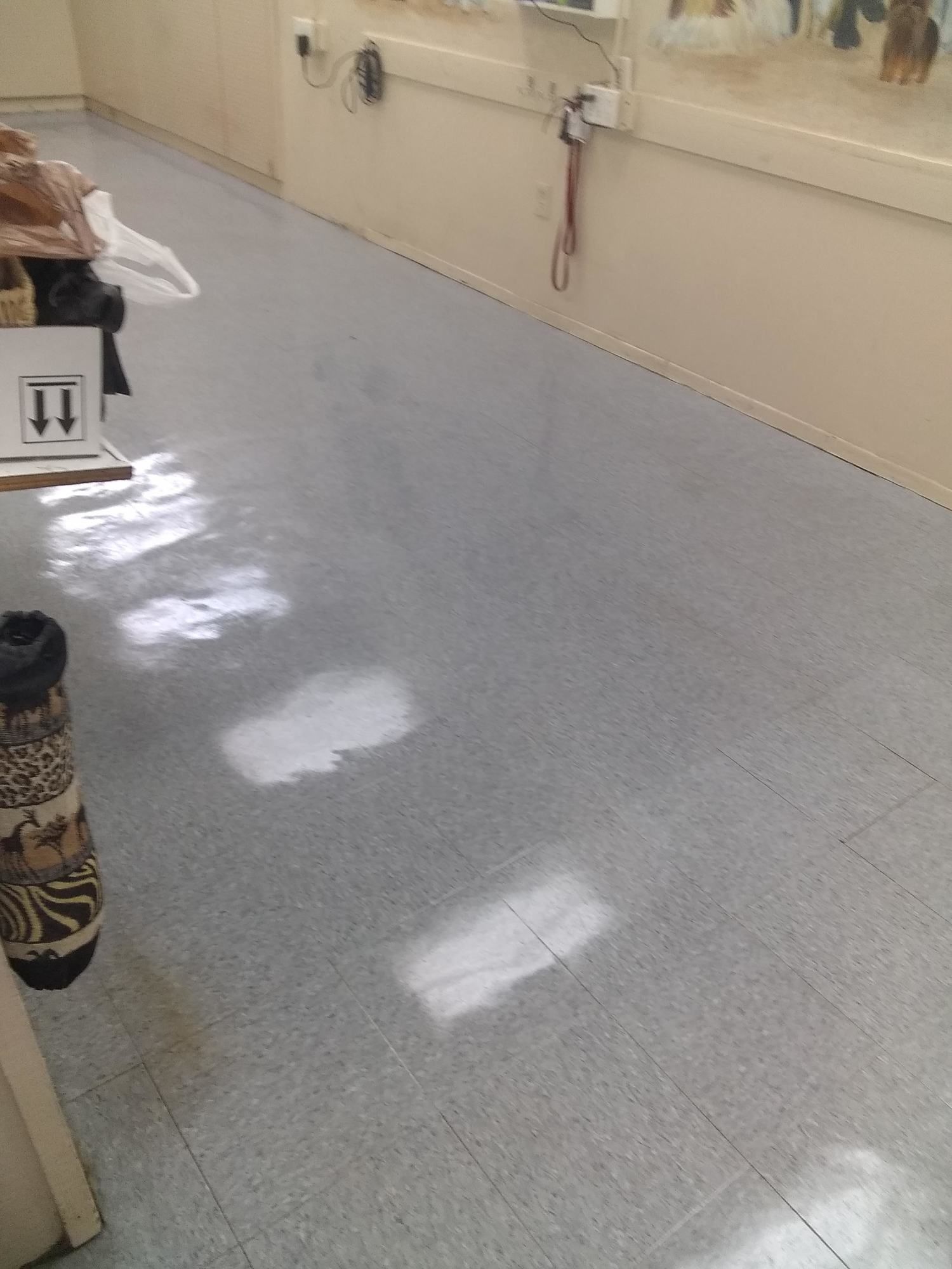 A gray tiled floor in a hallway with a stethoscope on the wall.