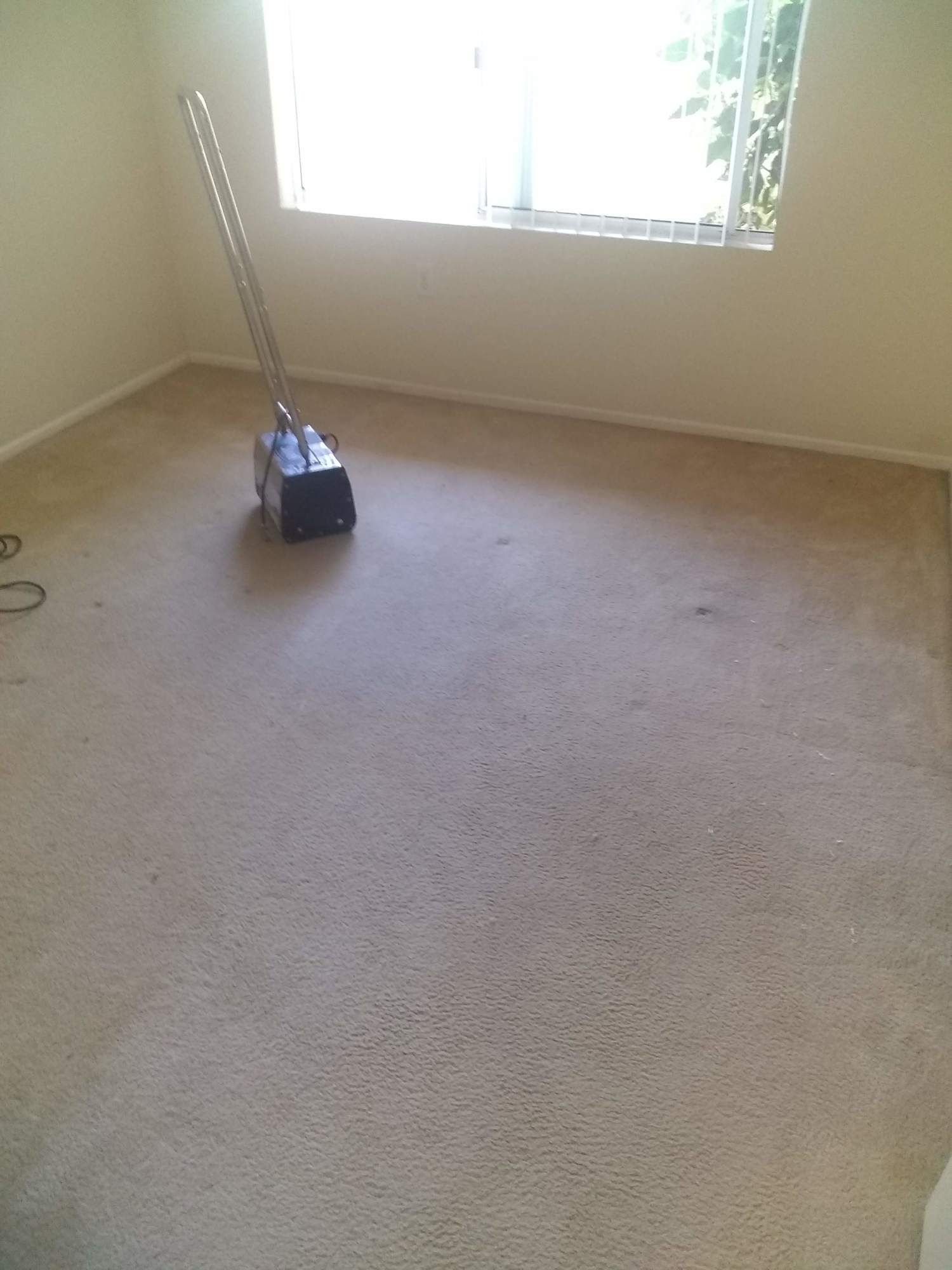 A vacuum cleaner is sitting on the floor of a room next to a window.