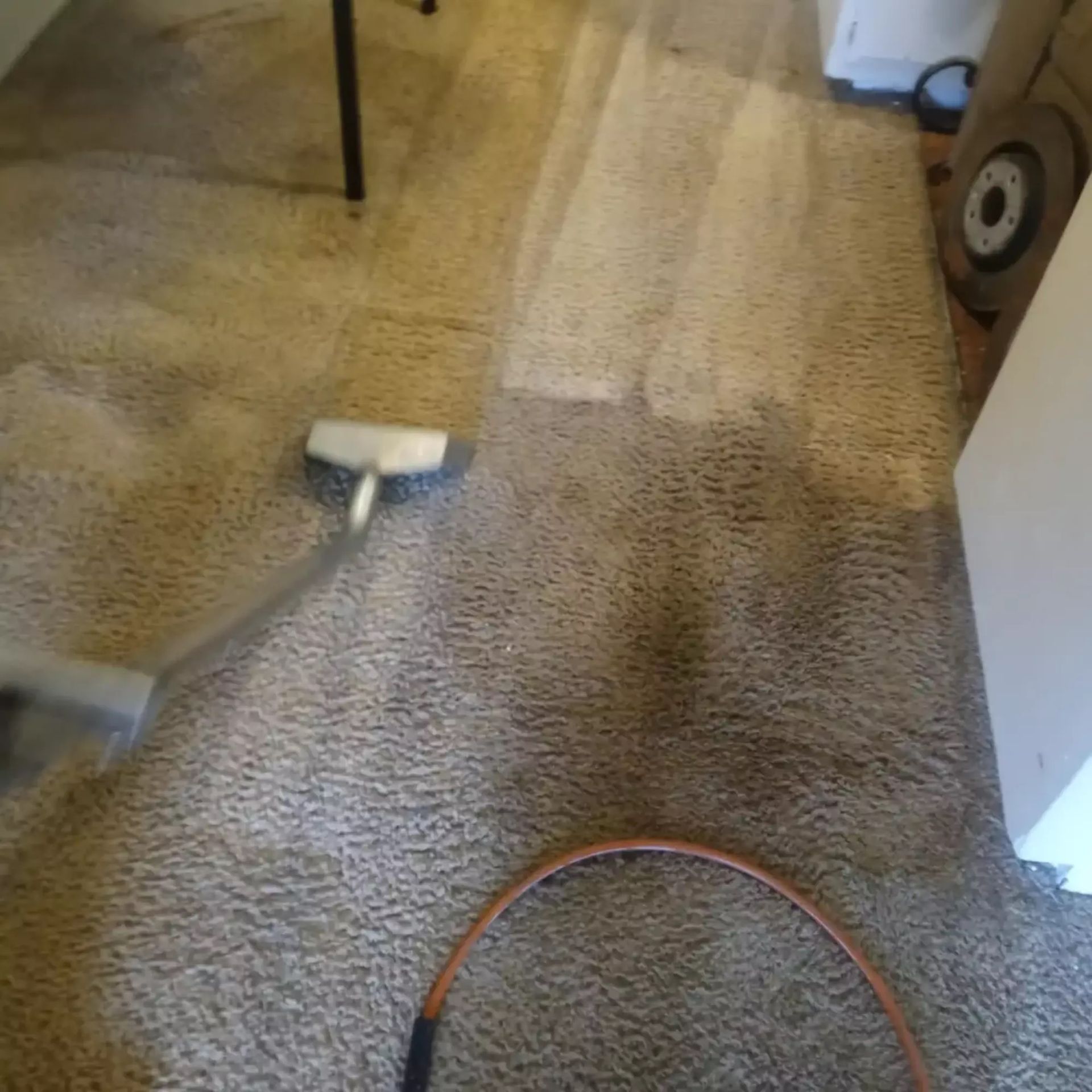 A vacuum cleaner is being used to clean a carpet in a room.