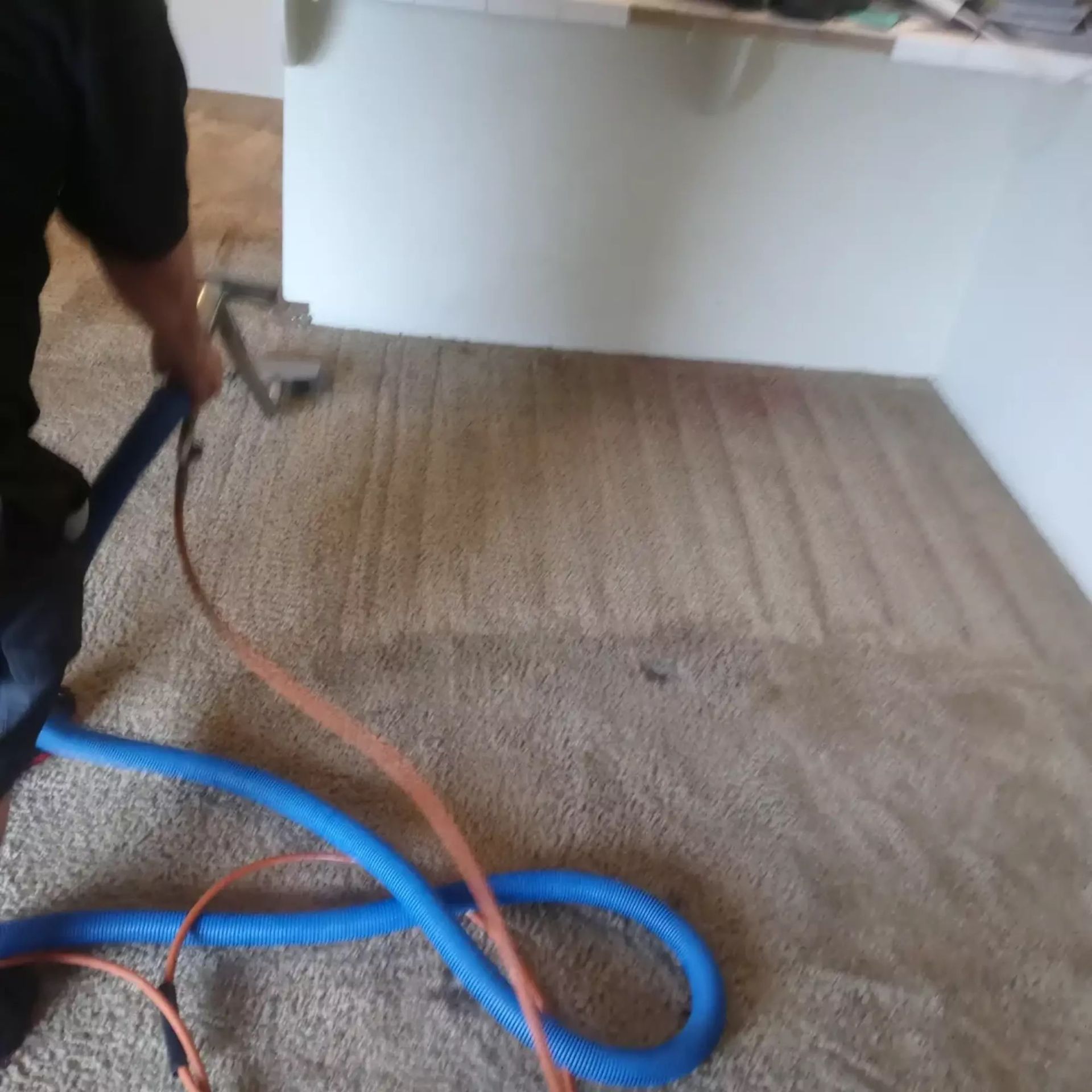 A man is cleaning a carpet with a vacuum cleaner