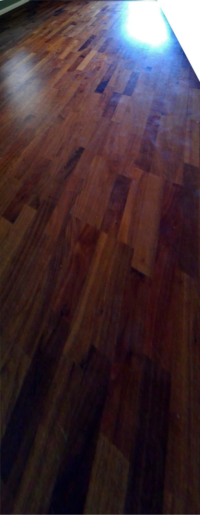 A close up of a wooden floor with a window in the background.