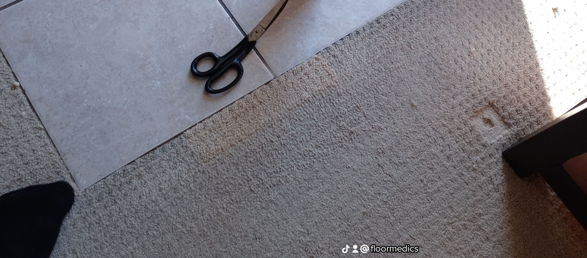 A pair of scissors laying on a tiled floor