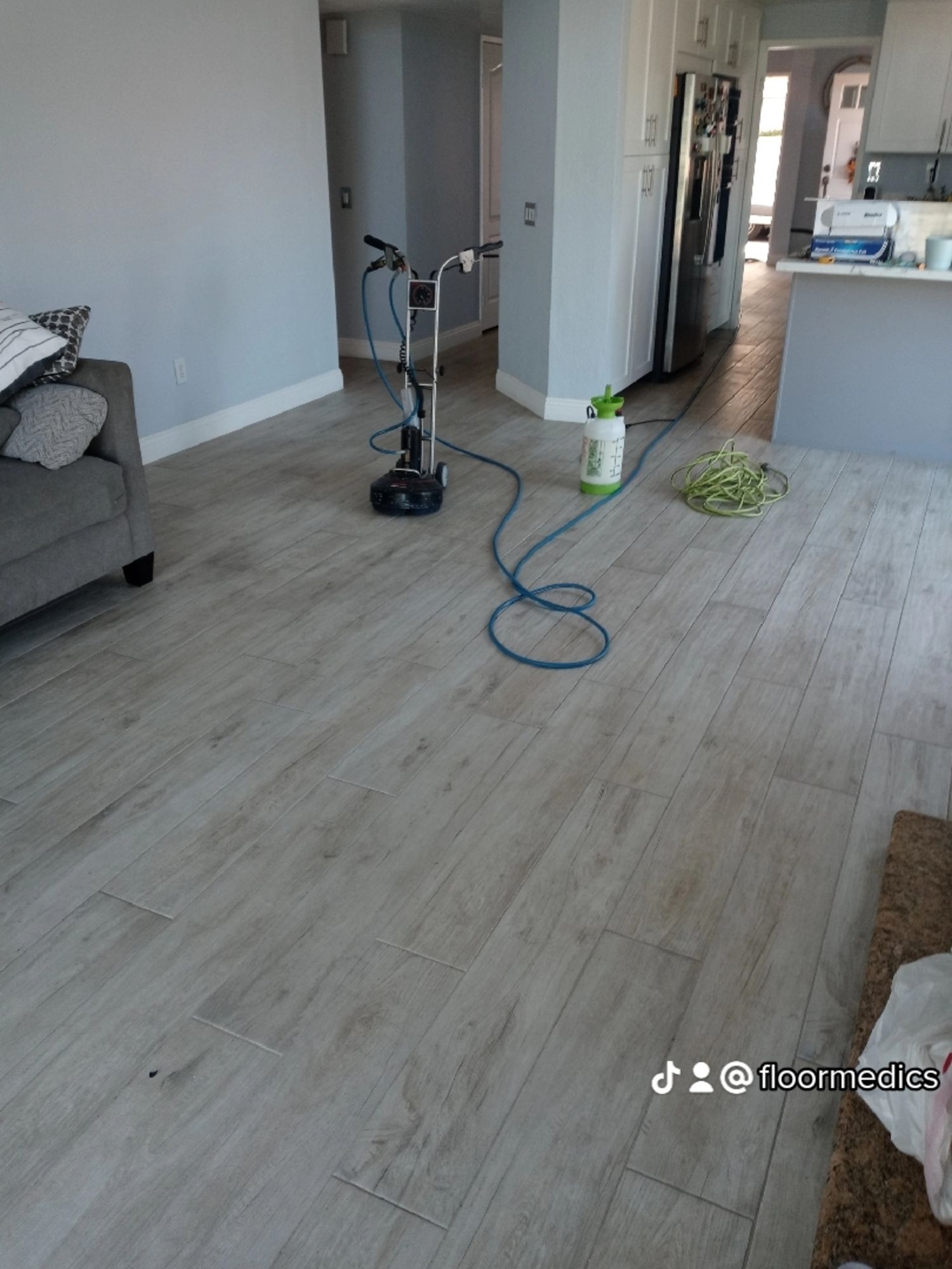 A vacuum cleaner is sitting on a wooden floor in a living room.