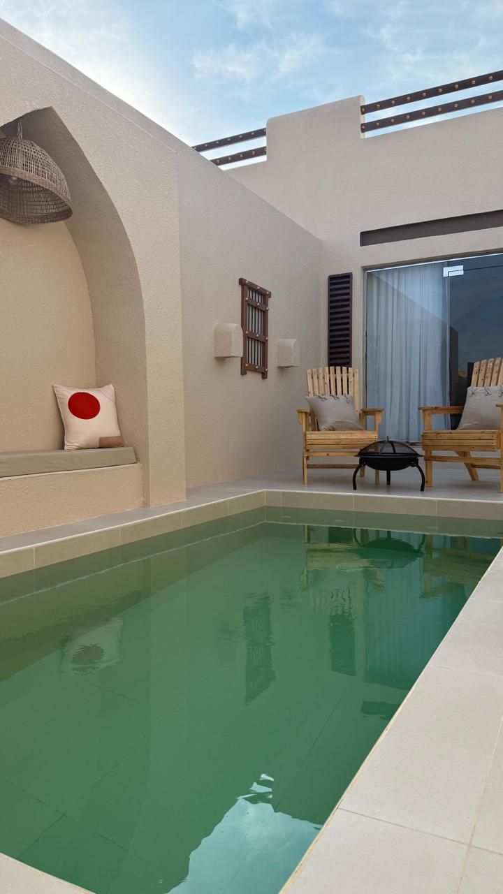 Small outdoor pool area with chairs, a decorative niche, and white walls.