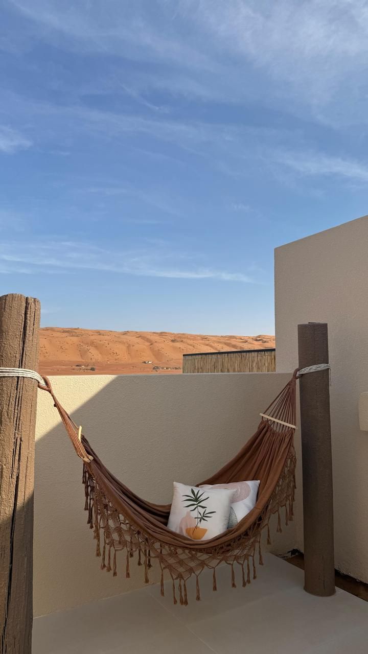 Hammock on a patio with a desert landscape in the background, under a blue sky.