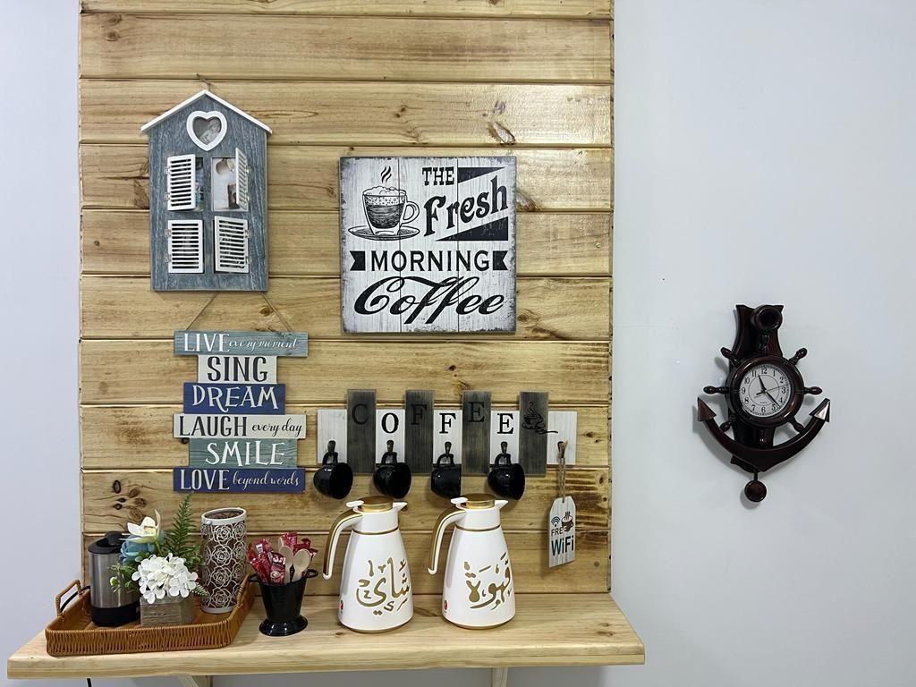 Coffee station with wooden backdrop, decor, and shelf. Includes mugs, coffee pots, and clock.