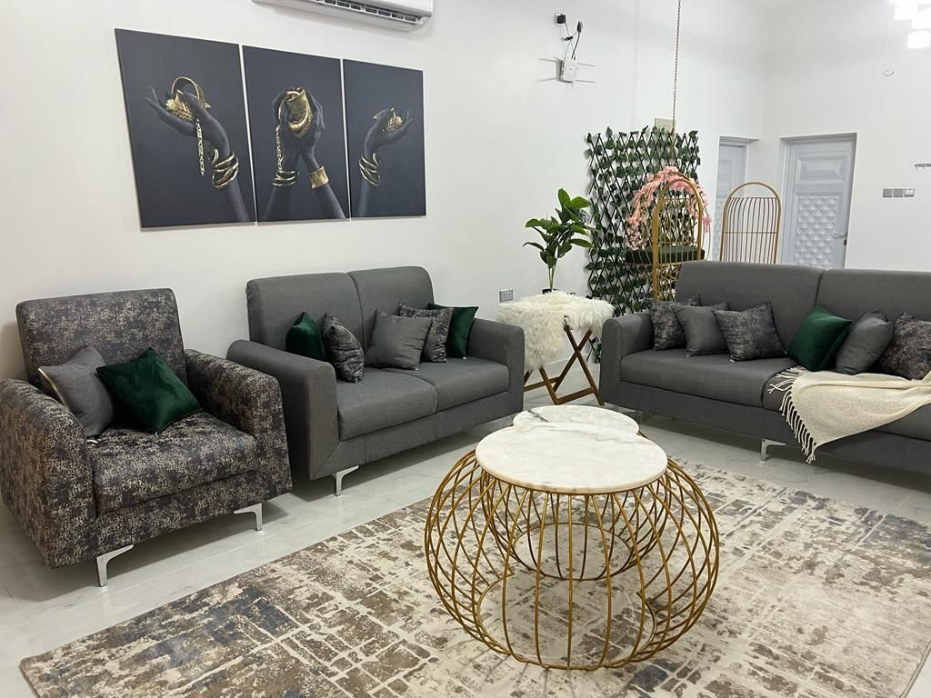 Living room with gray sofas, patterned armchair, gold coffee table, and abstract wall art.