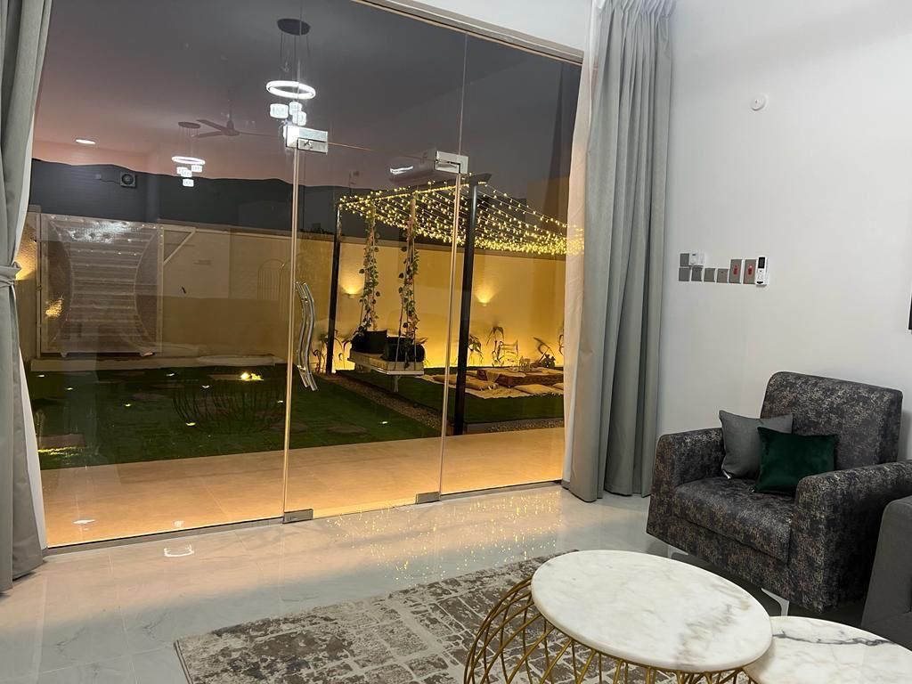 Living room with glass doors open to a lit backyard with swing and seating.