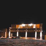 Night view of a modern building with illuminated pillars and a dark sky.
