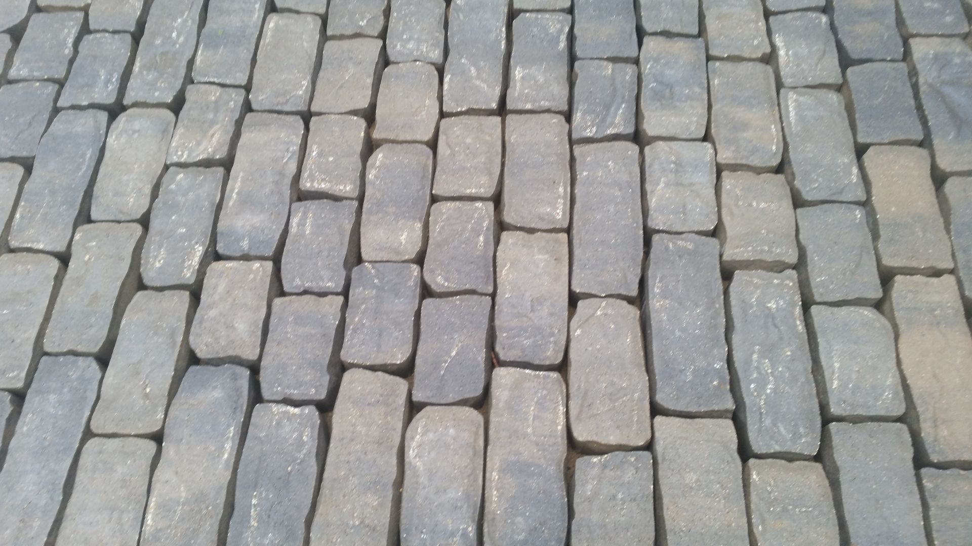 A repeating pattern of weathered, rectangular gray stone pavers laid in a staggered, brick-like arrangement.