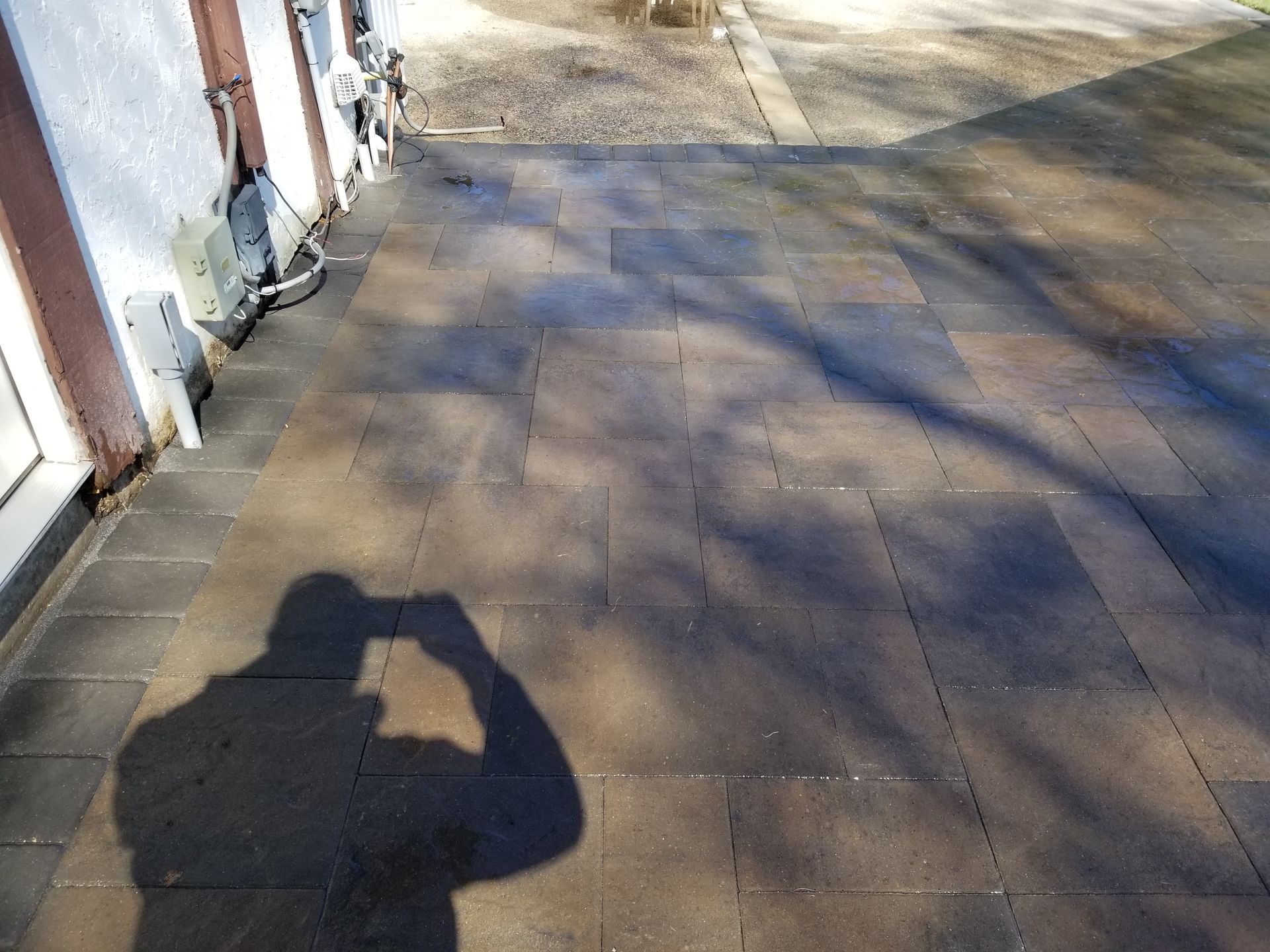 A stone patio area with a person's shadow cast over it, viewed from above.
