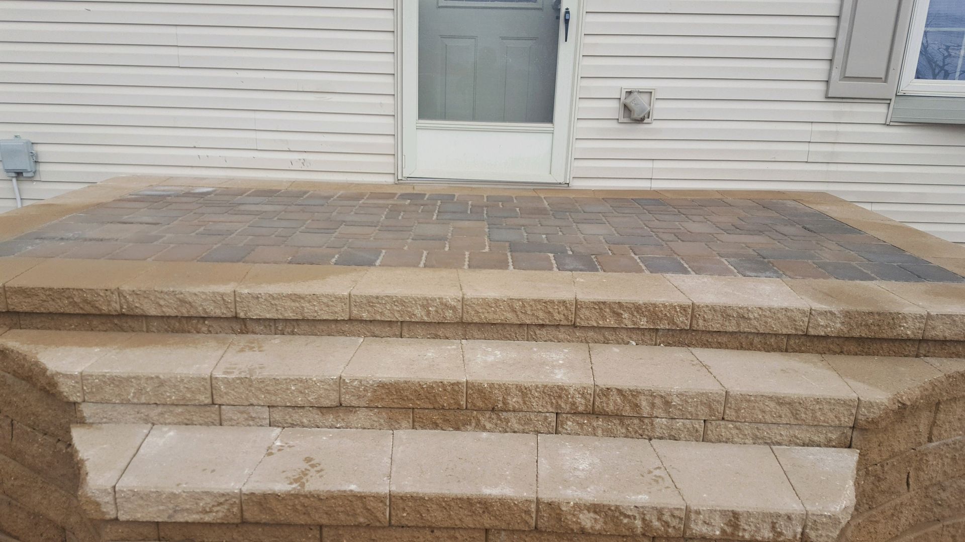 Stone stairs leading to a doorway, featuring a paved landing and beige, textured block steps.