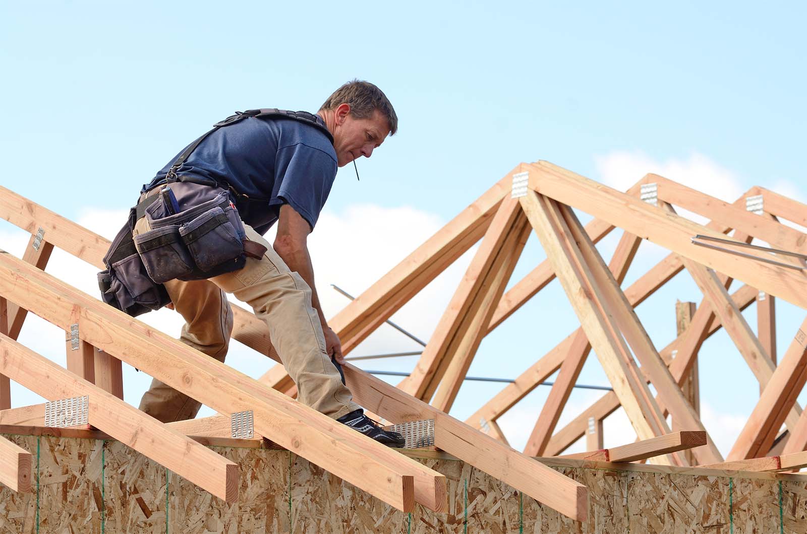 Carpenter On A Roof Securing Timber Roof Trusses