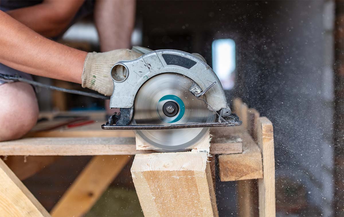 A Carpenter Using A Circular Saw To Build A Deck