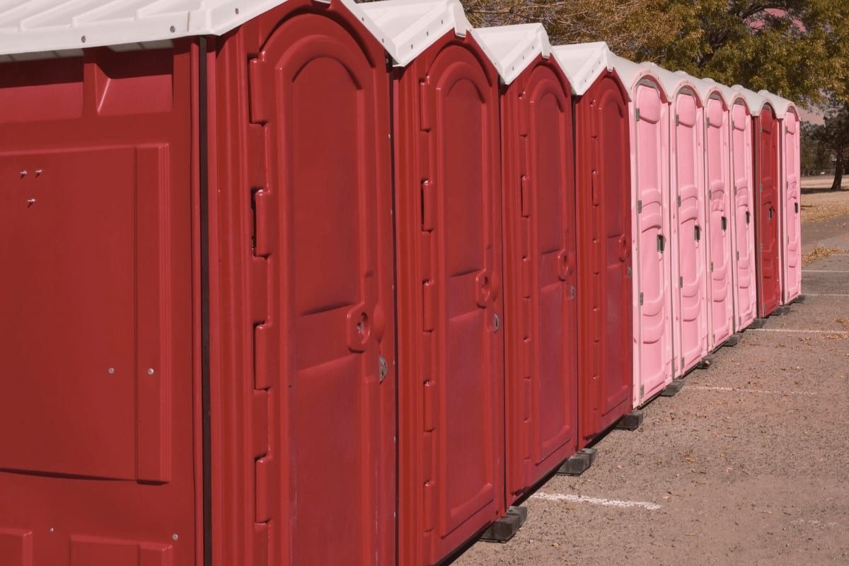 Row of red and pink portable toilets outdoors.