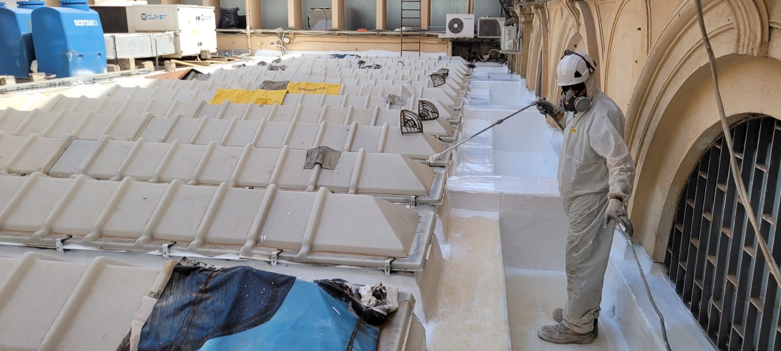 Un uomo sta spruzzando acqua su un tetto con uno spruzzatore.