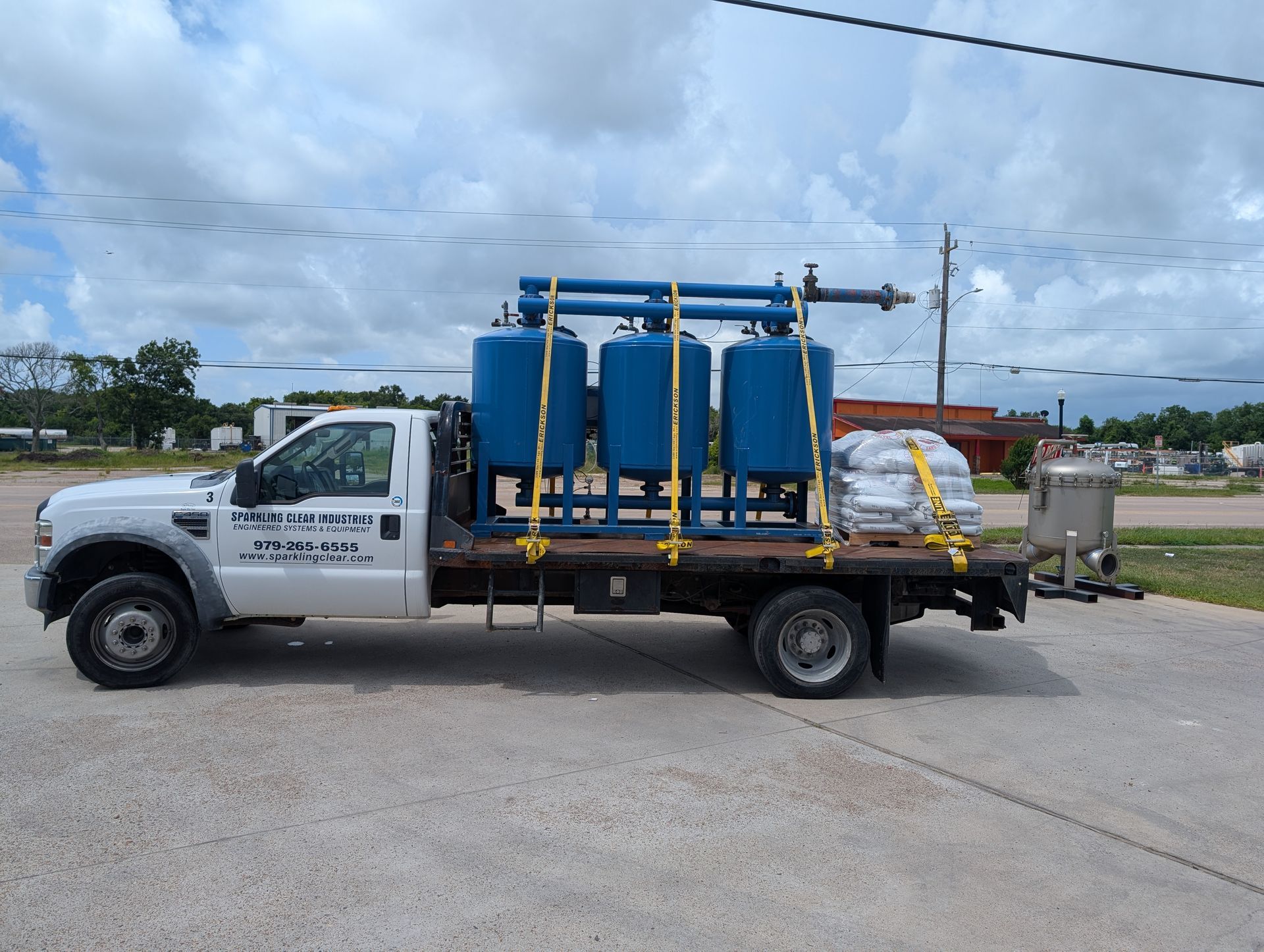 A white truck with sparkling clear's logo and blue filtration tanks on the back is loaded up and ready to go!