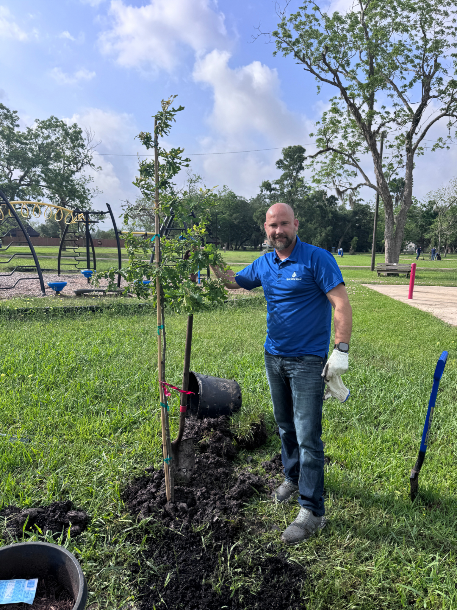 A man is standing next to a tree in a park.