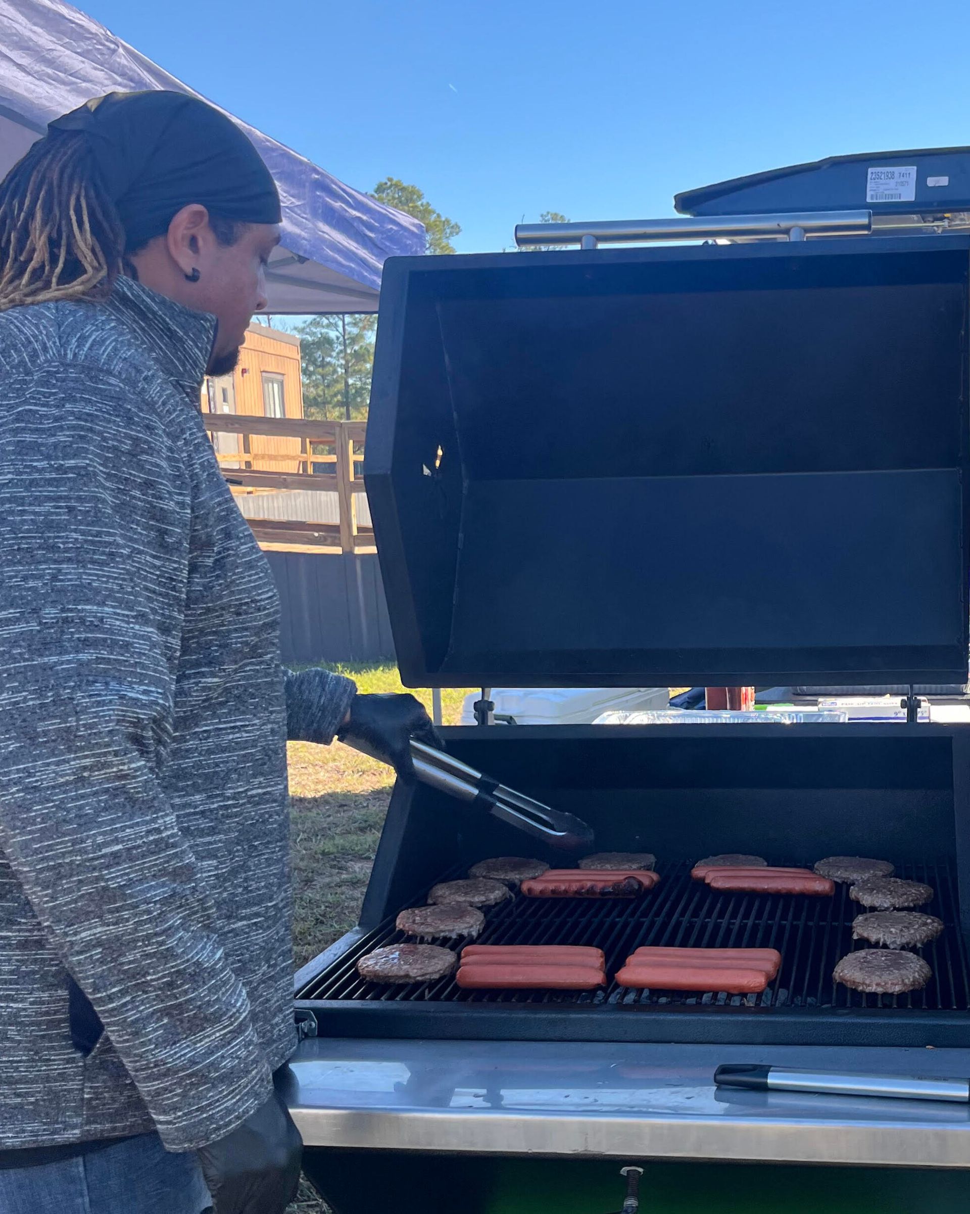 Person grilling hamburgers and hot dogs outdoors.