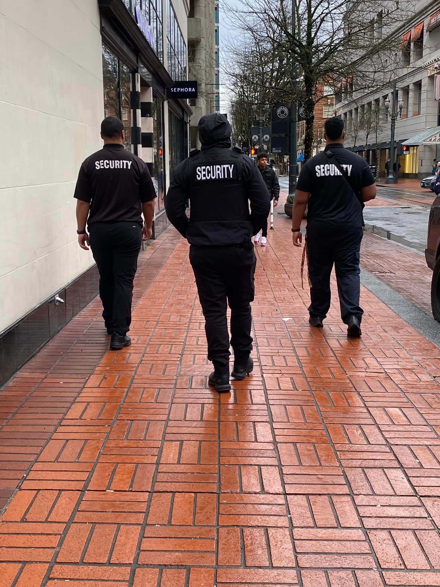 A group of men are walking down a brick sidewalk.