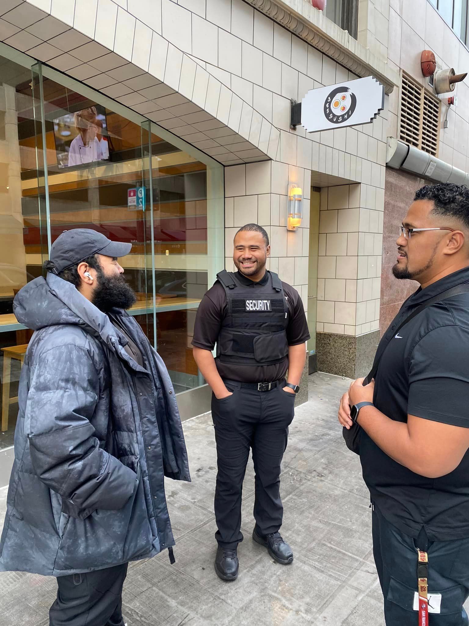 Three men are standing in front of a building talking to each other.