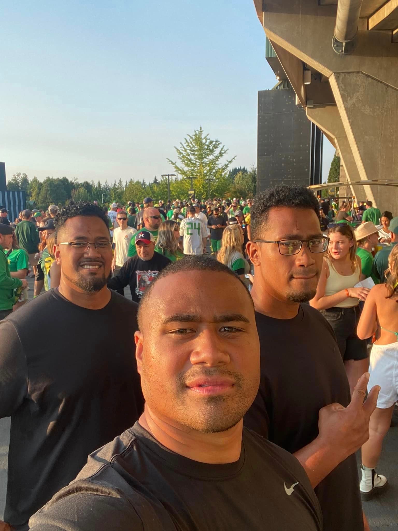 Three men are standing next to each other in front of a crowd of people.