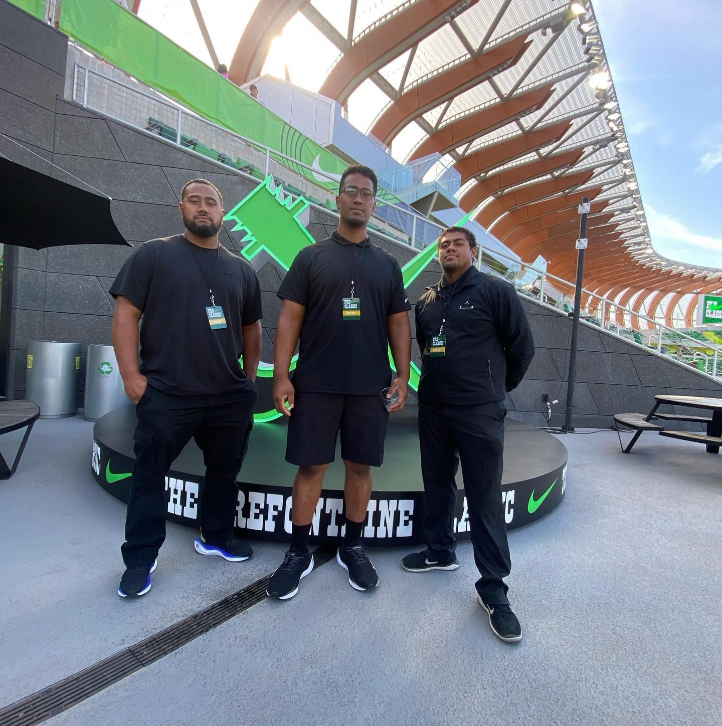 Three men are standing in front of a nike sign