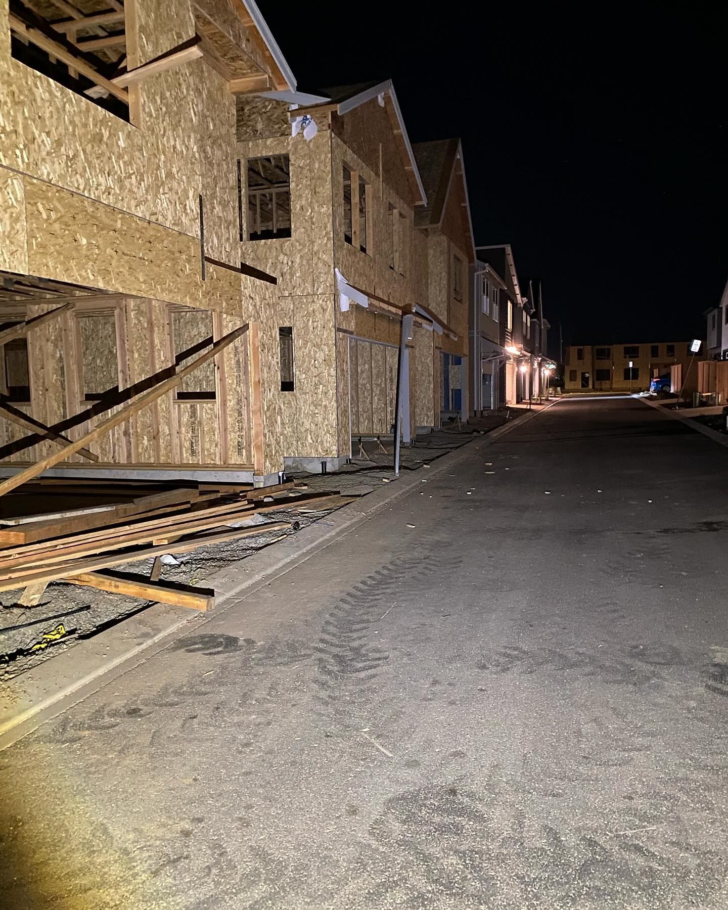 A row of houses under construction on a street at night.
