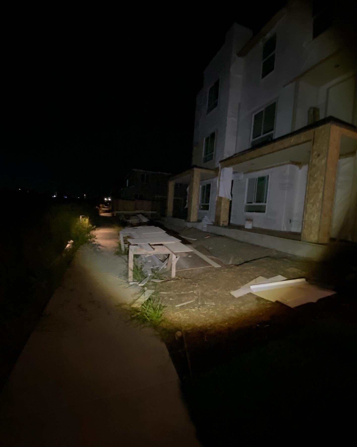 A person is walking down a sidewalk in front of a building at night.