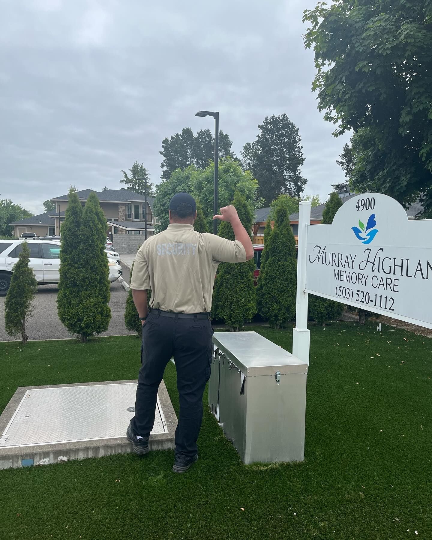 A man in a tan shirt is standing in front of a white sign.