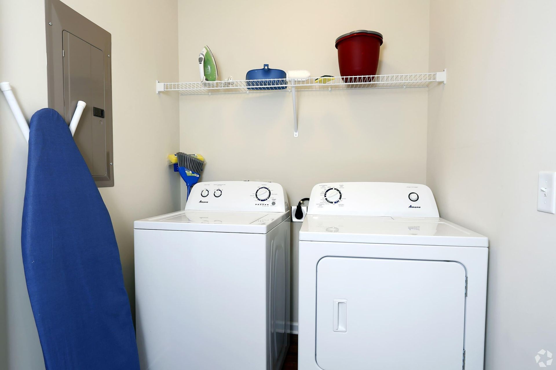 A laundry room with a washer and dryer and an ironing board.