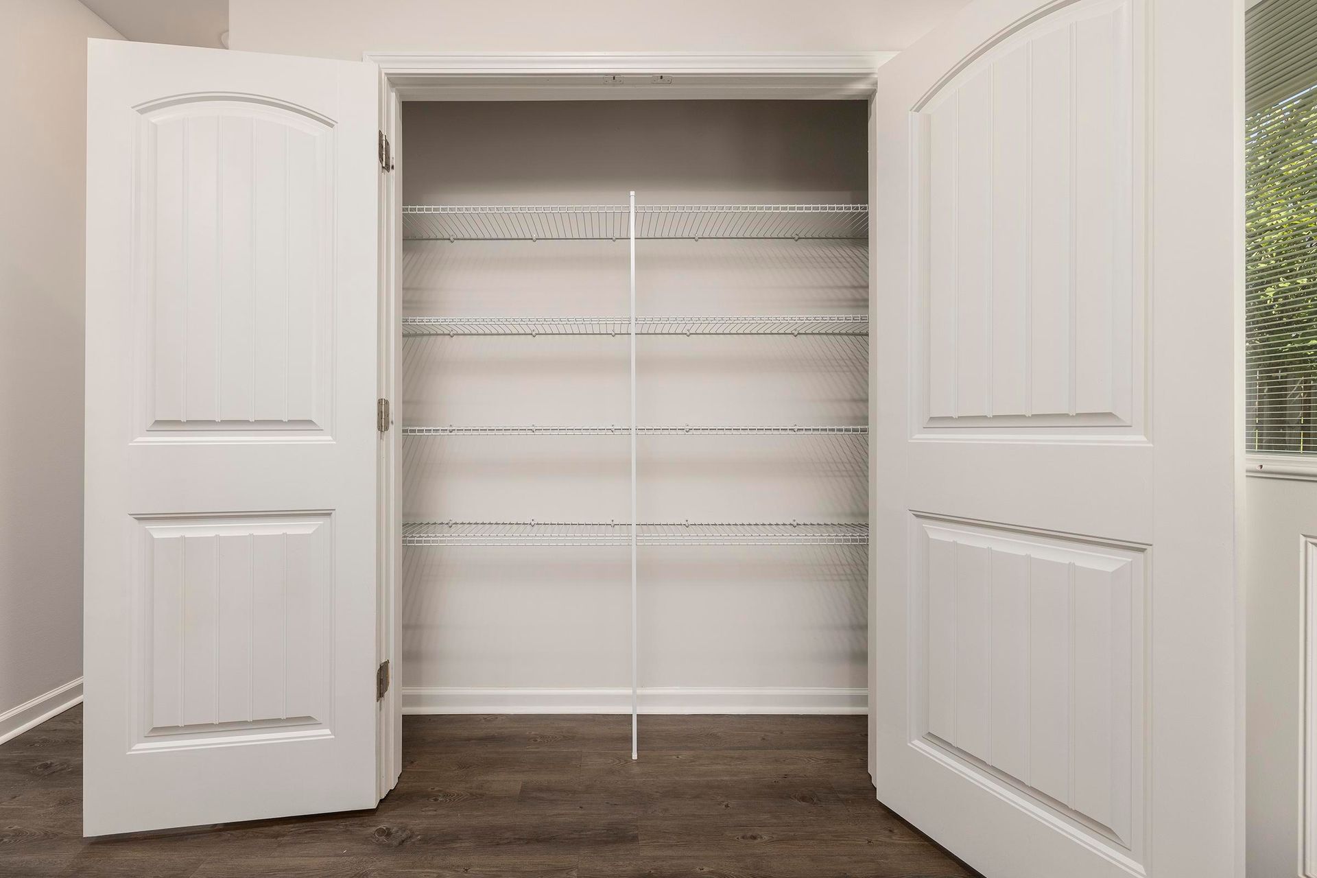 An empty walk in closet with white doors and shelves.