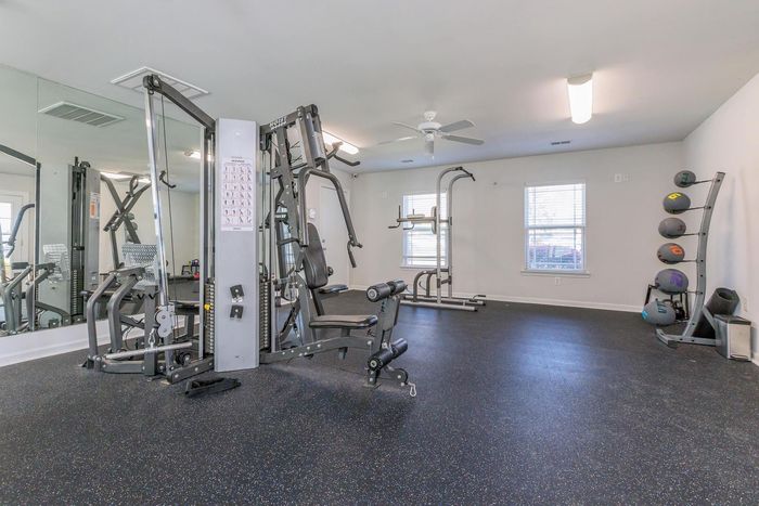 Gym with exercise machines, mirrors, and medicine balls on a black rubber floor.