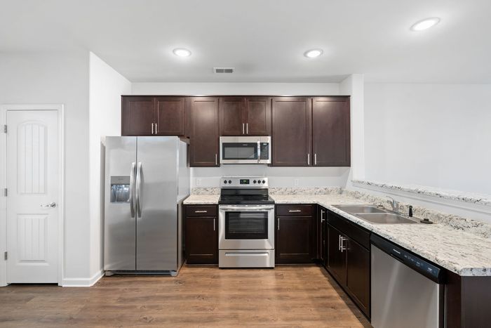 Kitchen with dark brown cabinets, stainless steel appliances, and granite countertops.