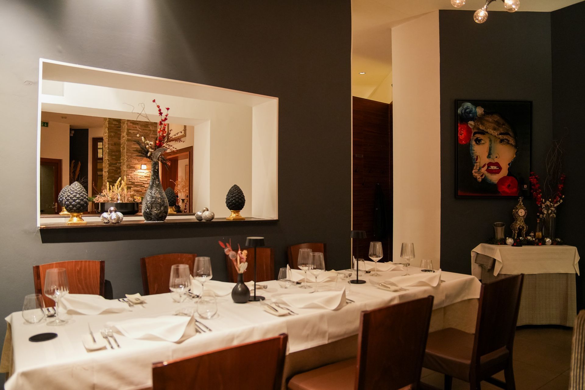 Ein formell gedeckter Esstisch in einem Restaurant mit dunkelgrauen Wänden, Spiegel und Kunstwerken.