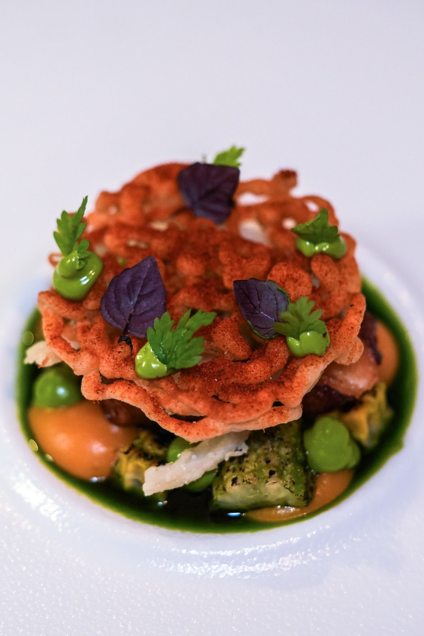 Eine Person hält ein Holztablett mit violetten Lebensmitteln, möglicherweise essbaren Blüten oder Gewürzen.