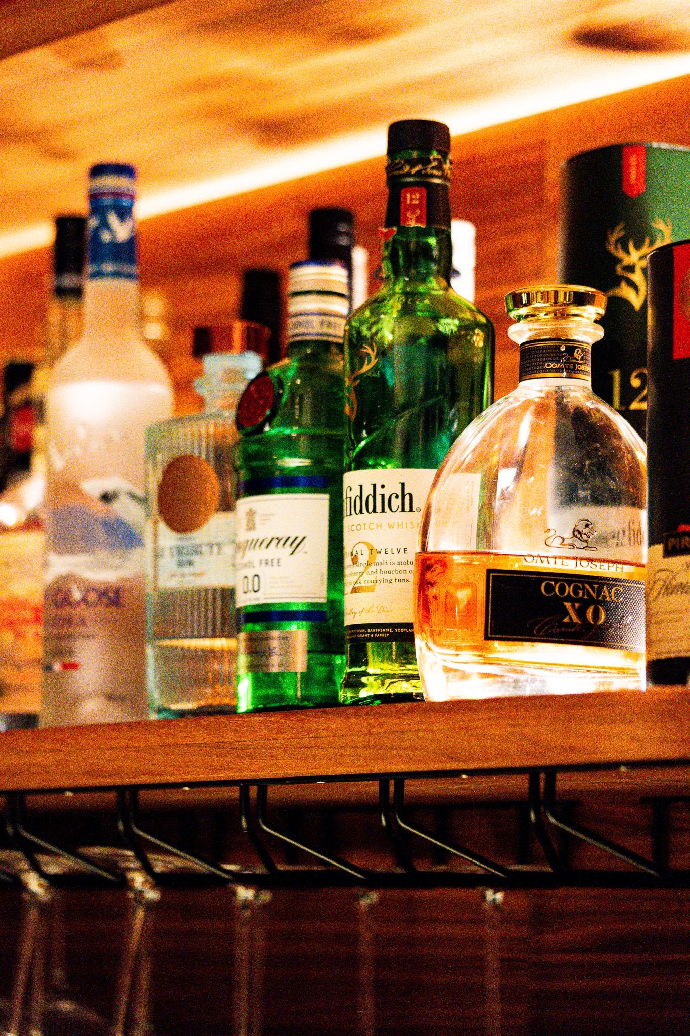 Spirituosenflaschen auf einem Barregal. Darunter Gin, Wodka und gereifte Spirituosen in verschiedenen Farben.