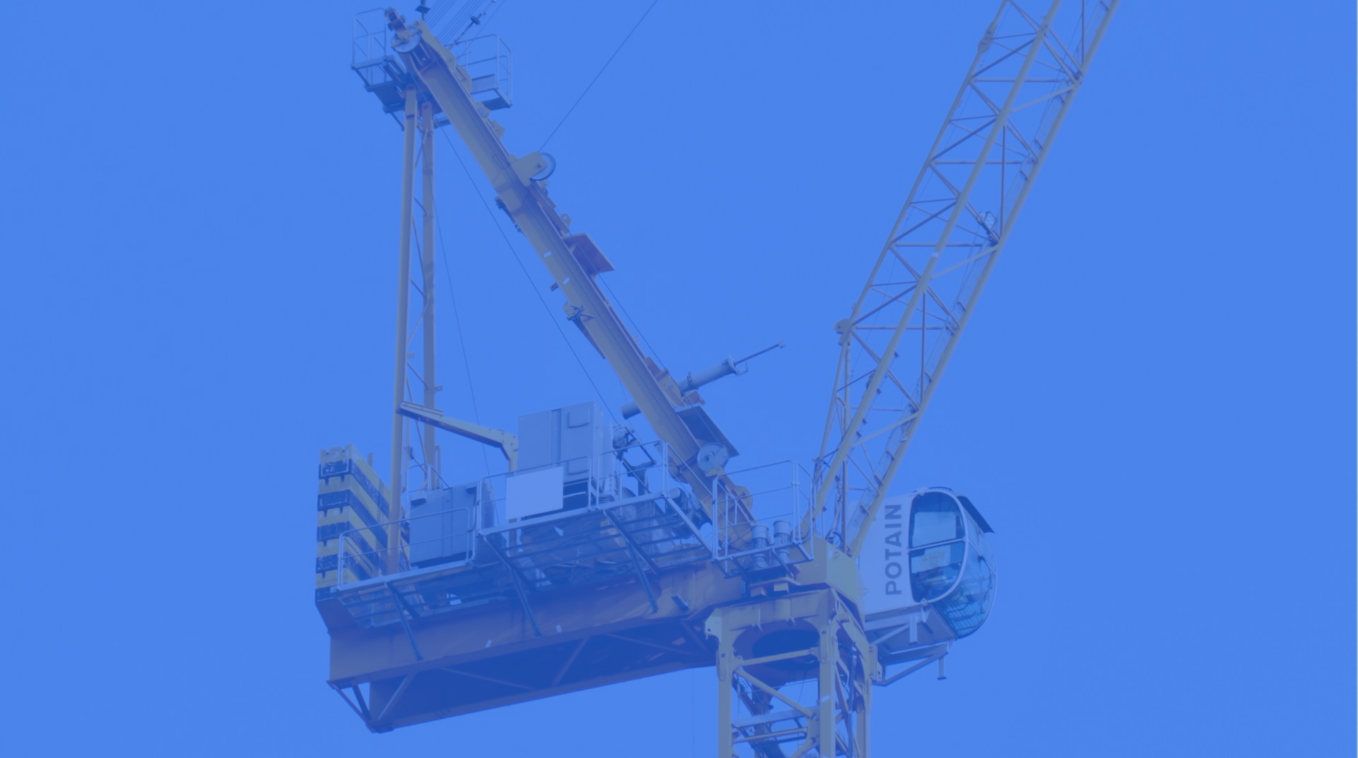Blue-toned construction crane lifting a suspended platform against the sky