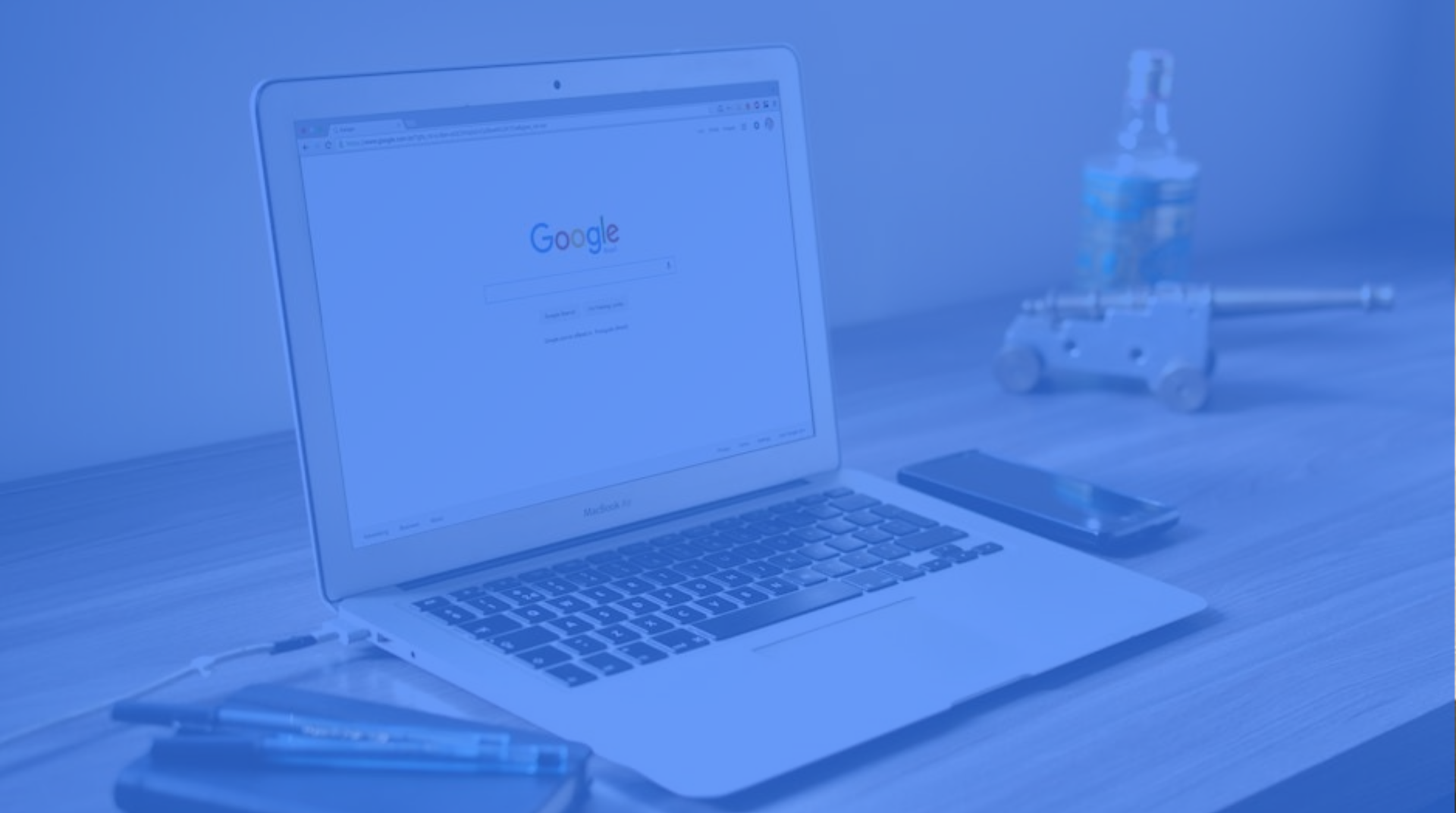 A laptop open on a desk with Google's homepage open.
