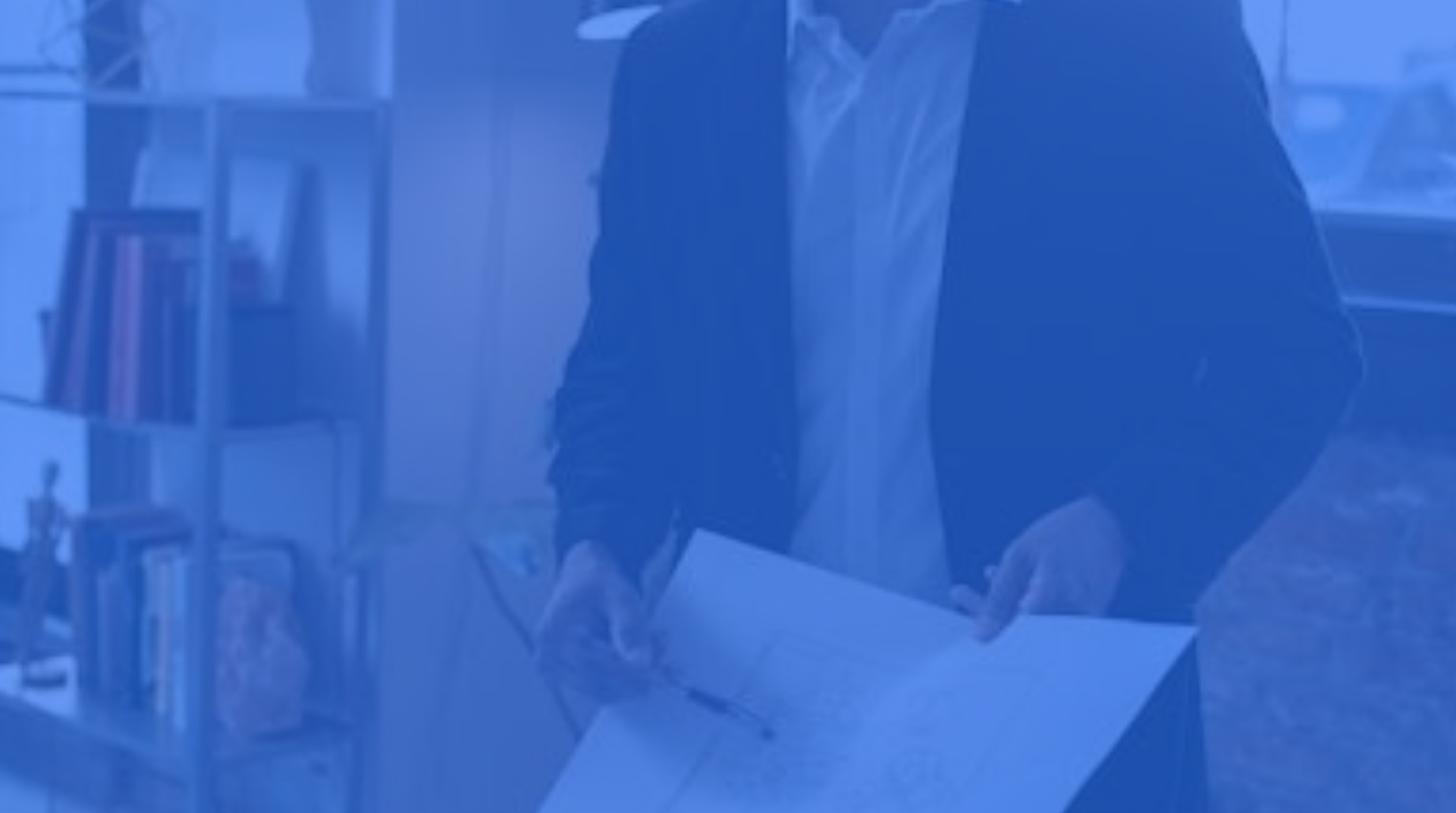 Civil engineer holding site build plan in an indoor office or library setting.