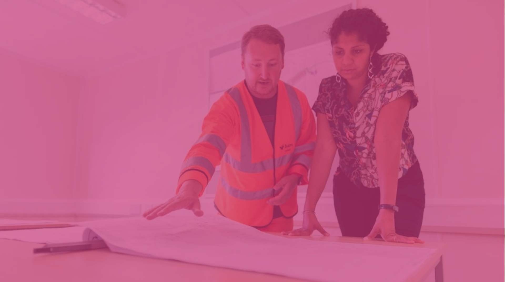 A civil engineer and a tradesperson in hi-vis looking at construction plans 