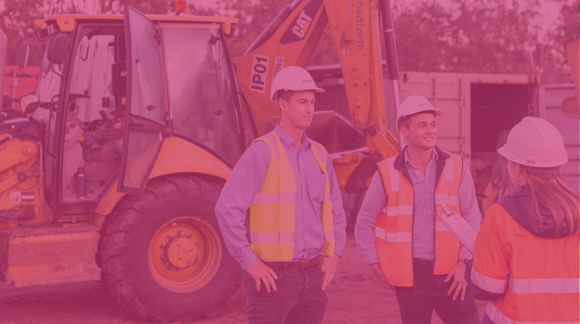 Three contractors standing next to a small excavator on a construction site.