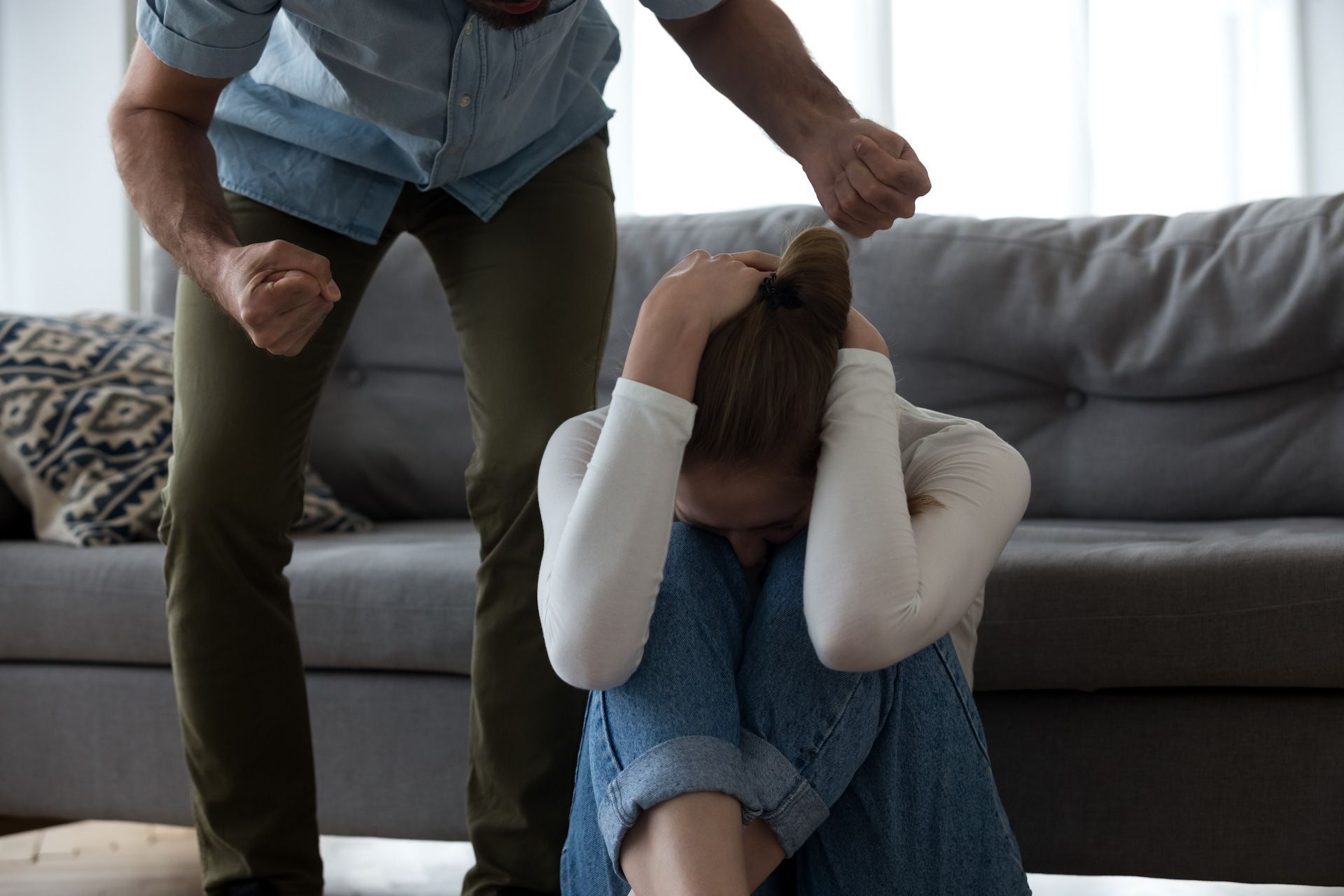 A man is standing next to a woman sitting on the floor.