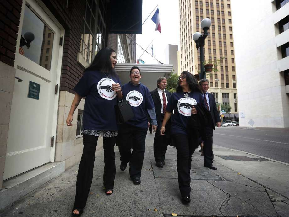 A group of people walking down a sidewalk wearing blue shirts with the letter e on them