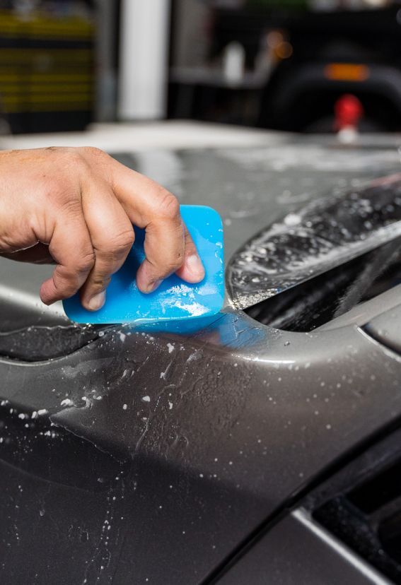 A person is cleaning a car with a blue sponge.