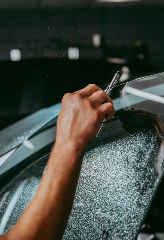A person is applying tinted glass to a car windshield.