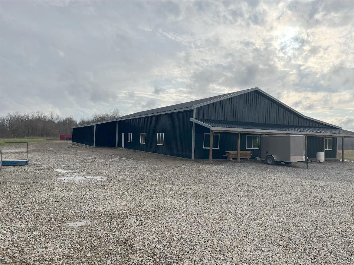A large black building is sitting on top of a gravel lot.