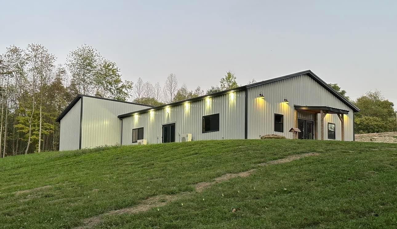 A large white building is sitting on top of a lush green hill.