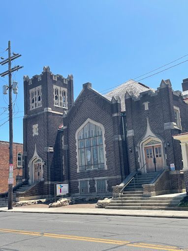 A large brick church is sitting on the corner of a street.