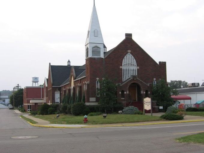 A brick church with a white steeple and a sign that says ' church ' on it